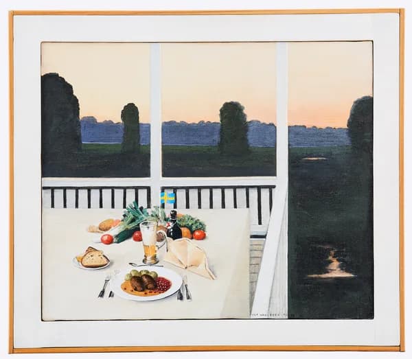 A set dinner table on a veranda at dusk, with a plate of meatballs, bread, vegetables, and a small Swedish flag, with a lake and forest visible in the background.