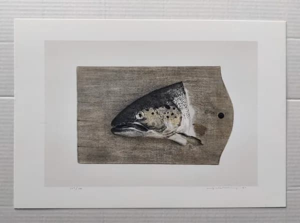 A sea trout's head shown lying on a wooden cutting board, in muted grey and brown tones.